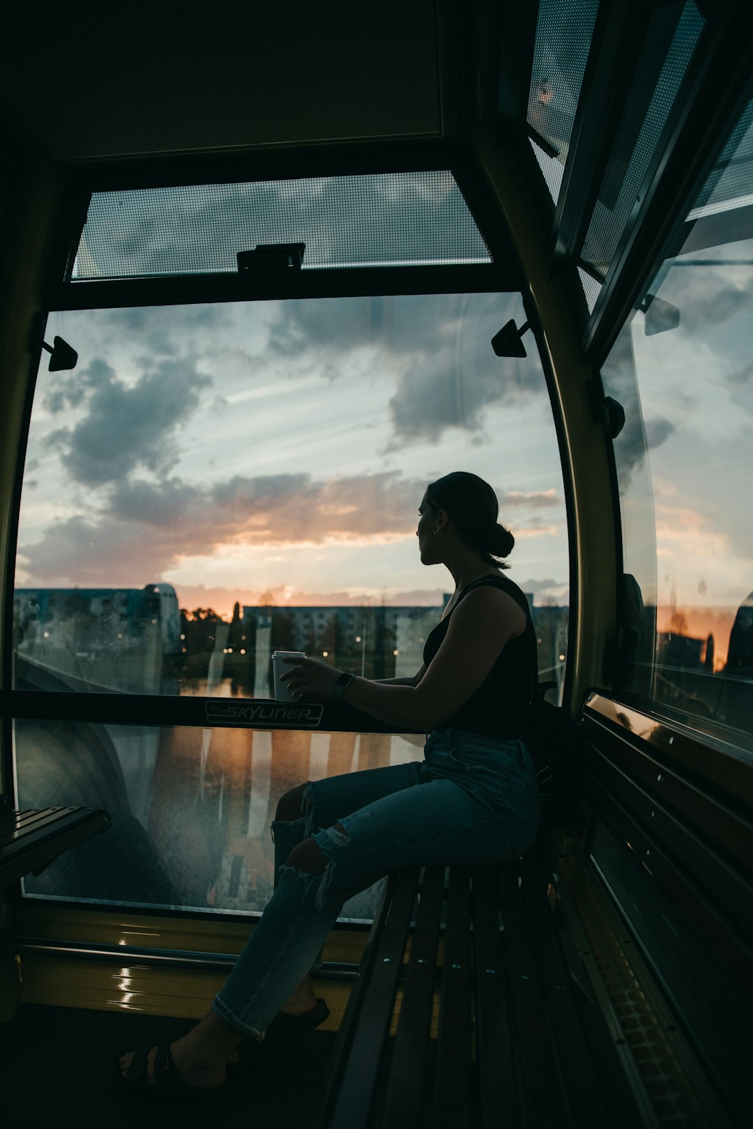 woman in black tank top sitting on window during daytime