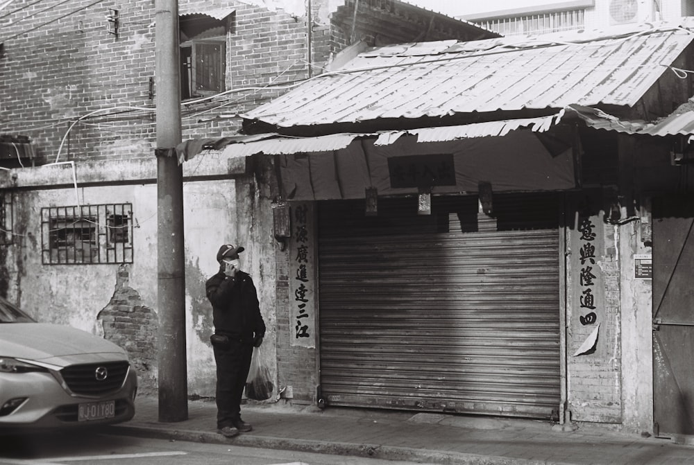 man in black jacket standing near brown wooden house during daytime