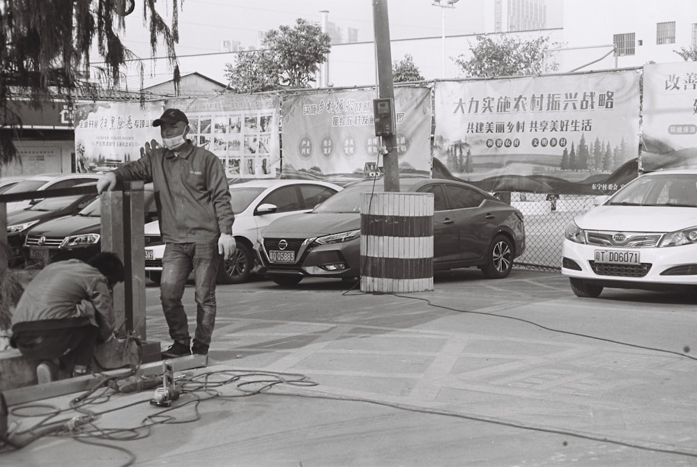 man in green button up shirt and gray pants standing beside white sedan during daytime