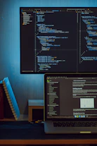 A computer monitor and laptop displaying Swift code and a programming tutorial