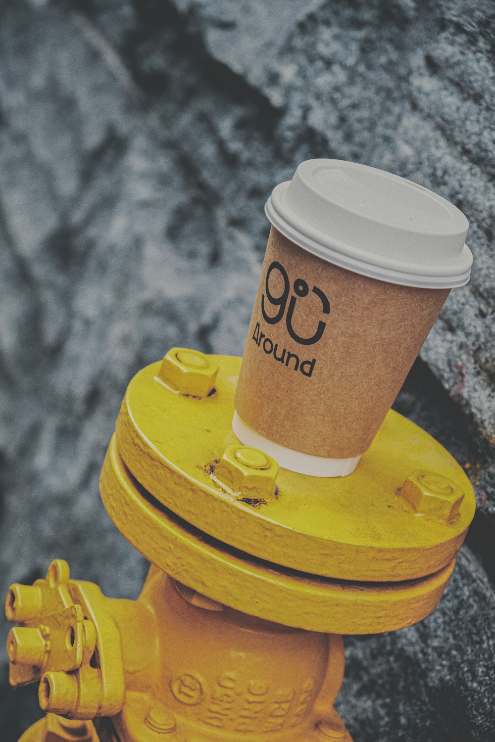 brown and white coffee cup on yellow round plastic lid