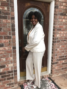 A friendly team member in royal blue and gold attire greeting a homeowner at their front door on a sunny day.