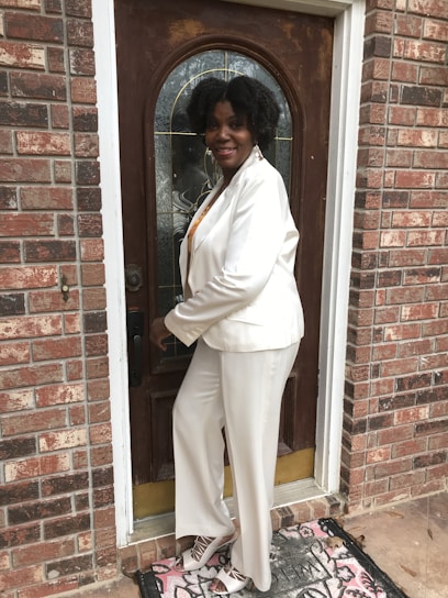 A friendly team member in royal blue and gold attire greeting a homeowner at their front door on a sunny day.