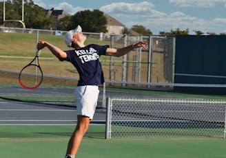 man in black shirt and white shorts playing tennis during daytime