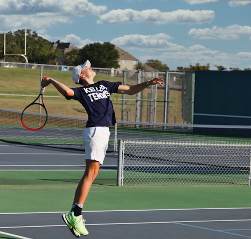 man in black shirt and white shorts playing tennis during daytime