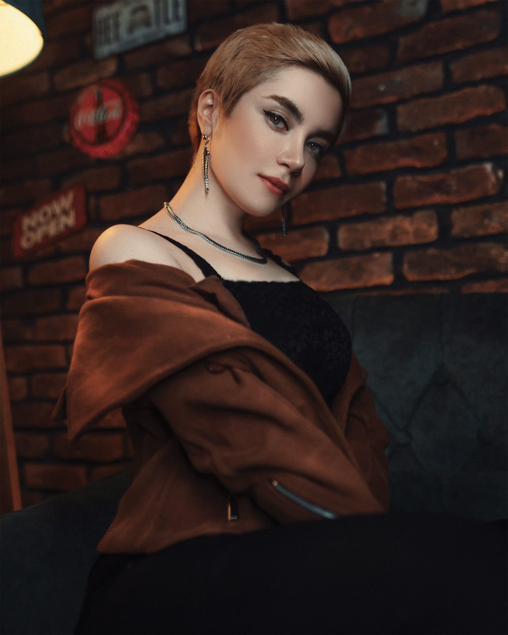 woman in brown coat standing near brown brick wall