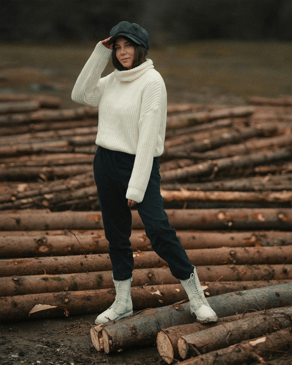 woman in white knit sweater and black pants standing on brown wooden stairs