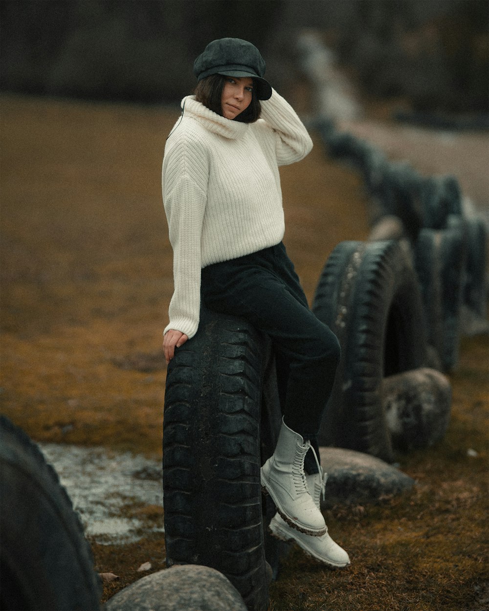 man in white sweater and blue denim jeans sitting on black tire