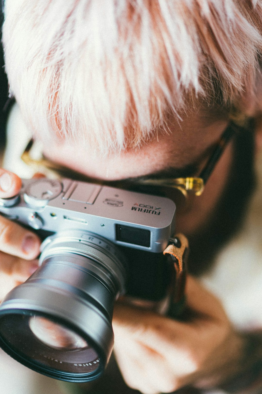 man in black framed eyeglasses holding gray and black camera