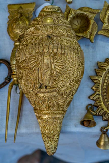 Close-up of a gold-painted conch resting on a handcrafted wooden stand, highlighting its intricate details.