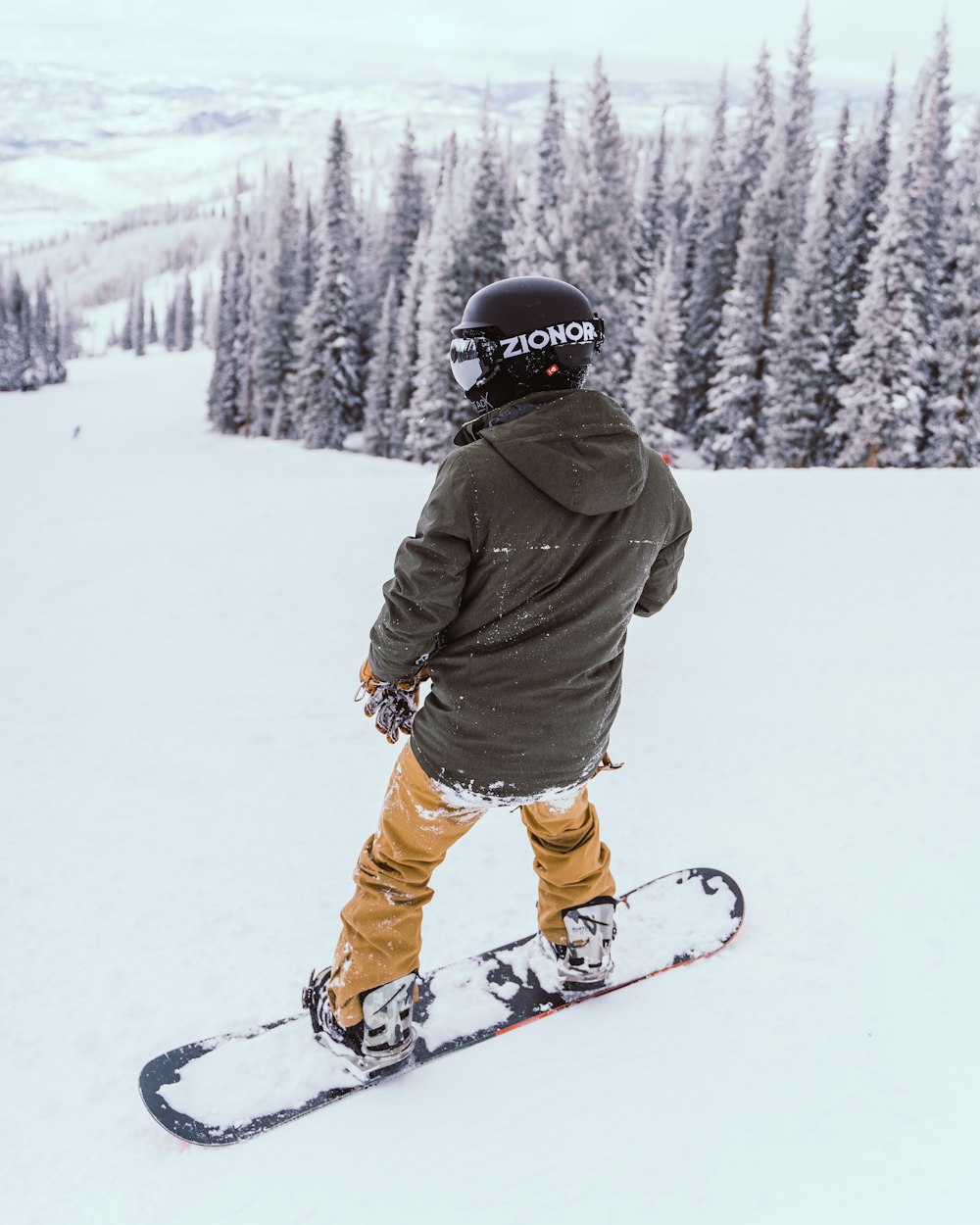 person in brown jacket and orange pants riding ski blades on snow covered ground during daytime