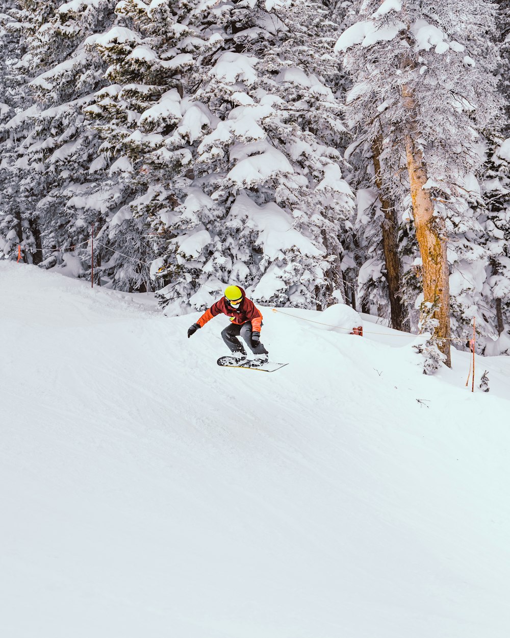 person in red jacket riding on snowboard on snow covered ground during daytime