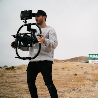 man in white long sleeve shirt holding black dslr camera