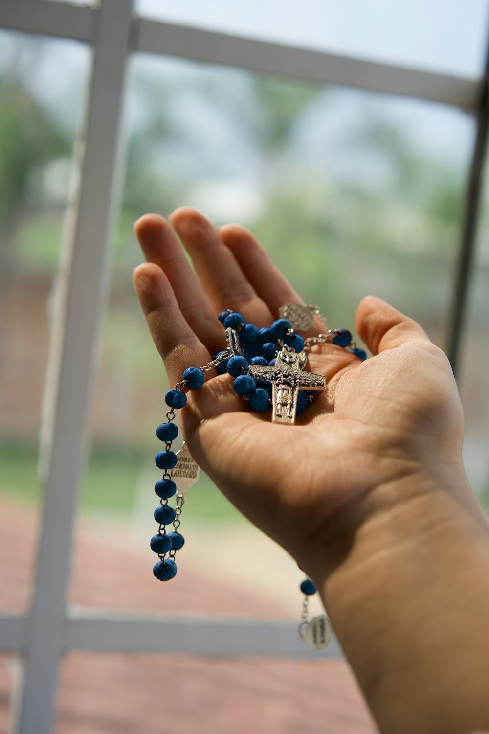 personne tenant un bracelet de perles bleues et argentées