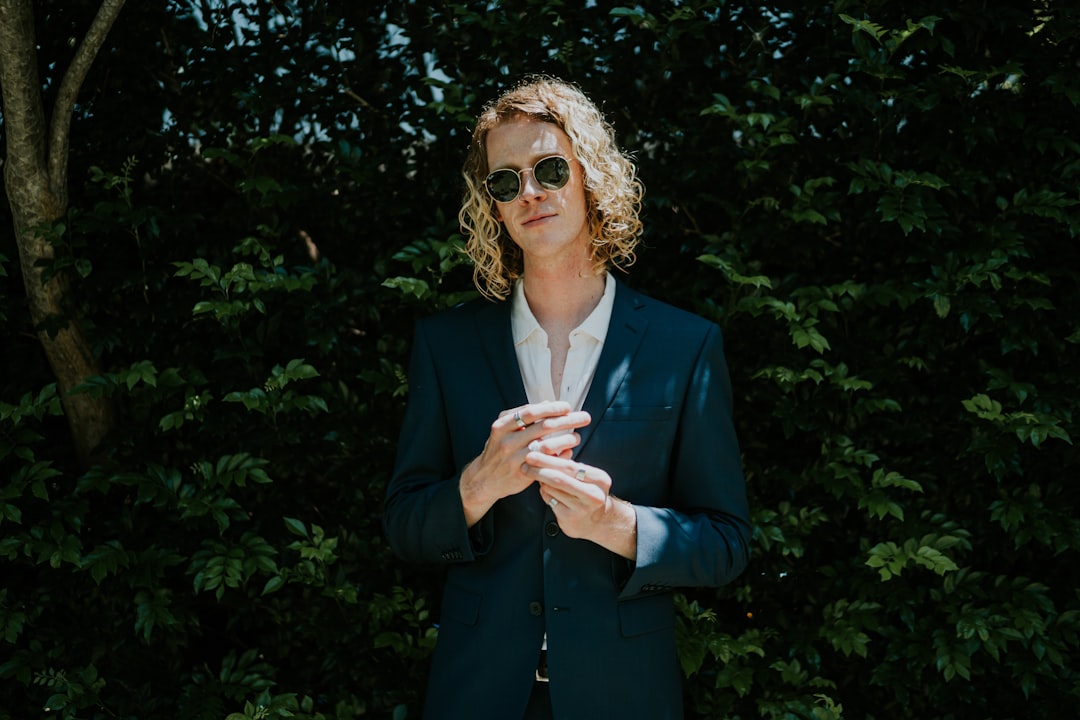 woman in blue blazer standing near green tree during daytime