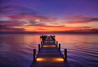 brown wooden dock on sea during sunset