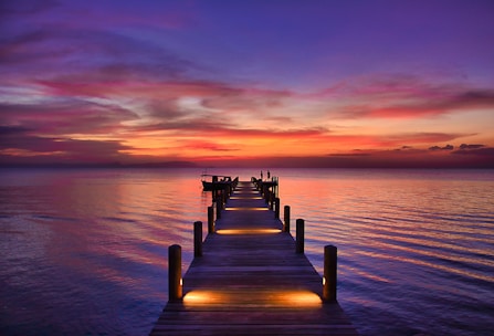 brown wooden dock on sea during sunset