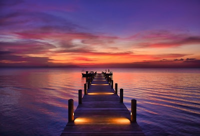 brown wooden dock on sea during sunset