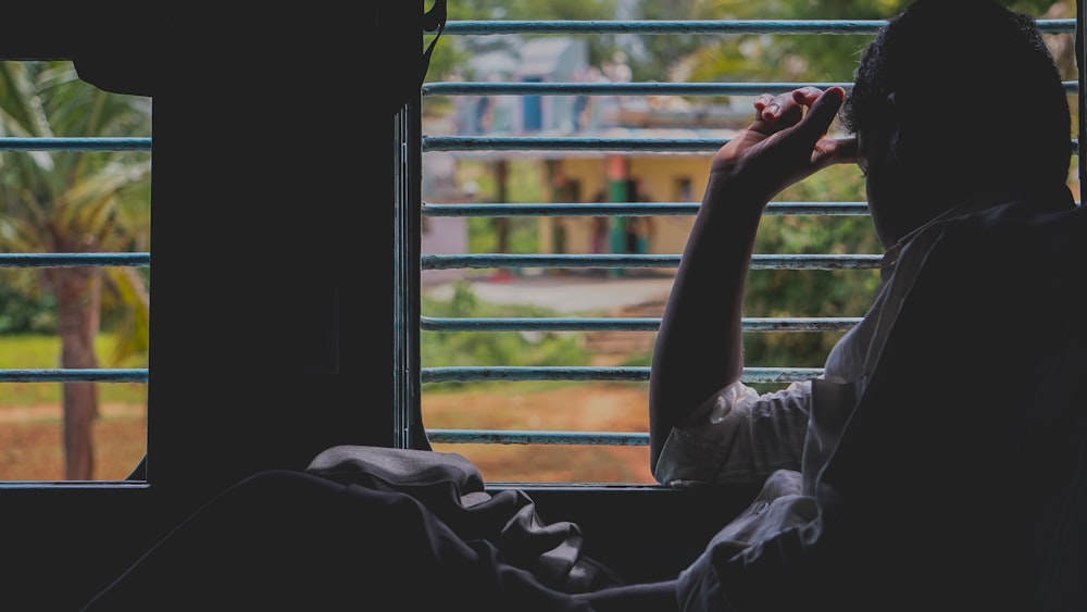 person in gray long sleeve shirt sitting on window