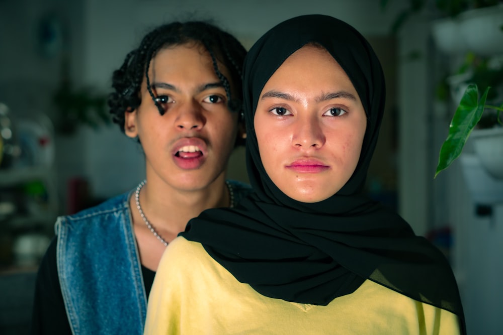 woman in black hijab beside woman in yellow shirt