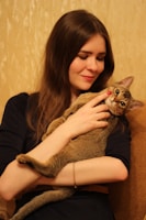 A happy adopter holding a newly adopted cat in a warm embrace.