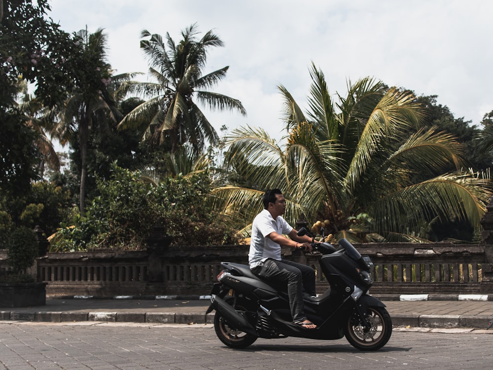 man in white shirt riding black motorcycle on road during daytime