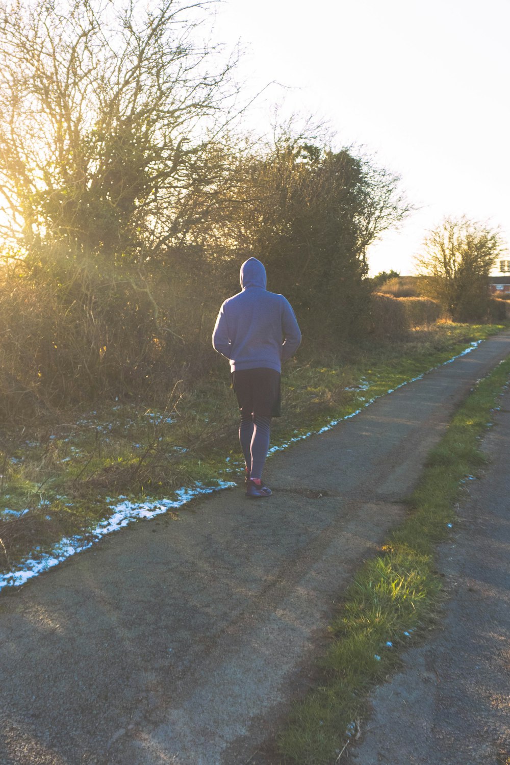 man in white hoodie walking on pathway during daytime