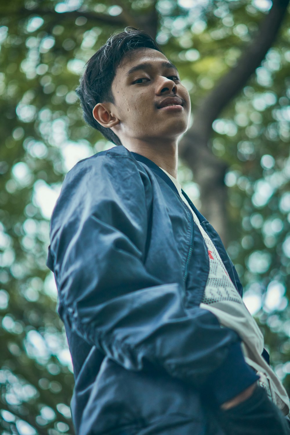 man in blue jacket standing near green trees during daytime