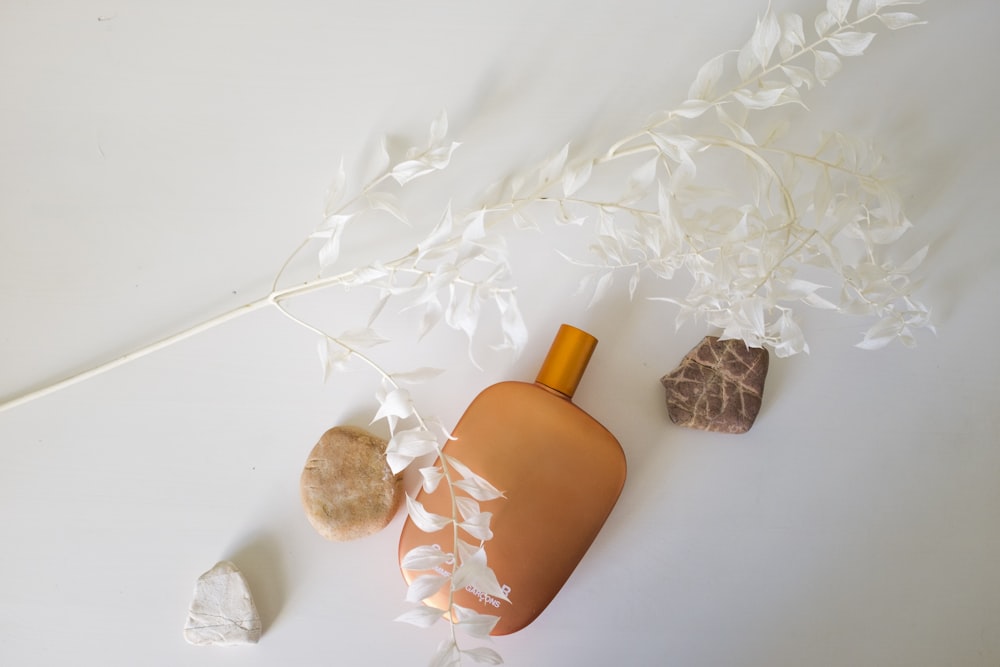 orange bottle beside white and brown floral textile