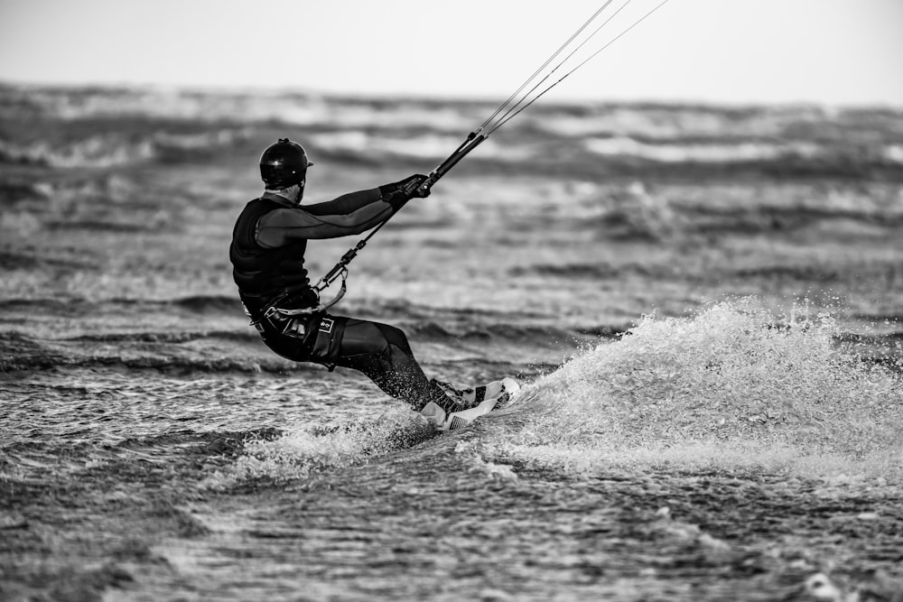 homme en veste noire et pantalon noir jouant à la planche à voile sur les vagues de la mer