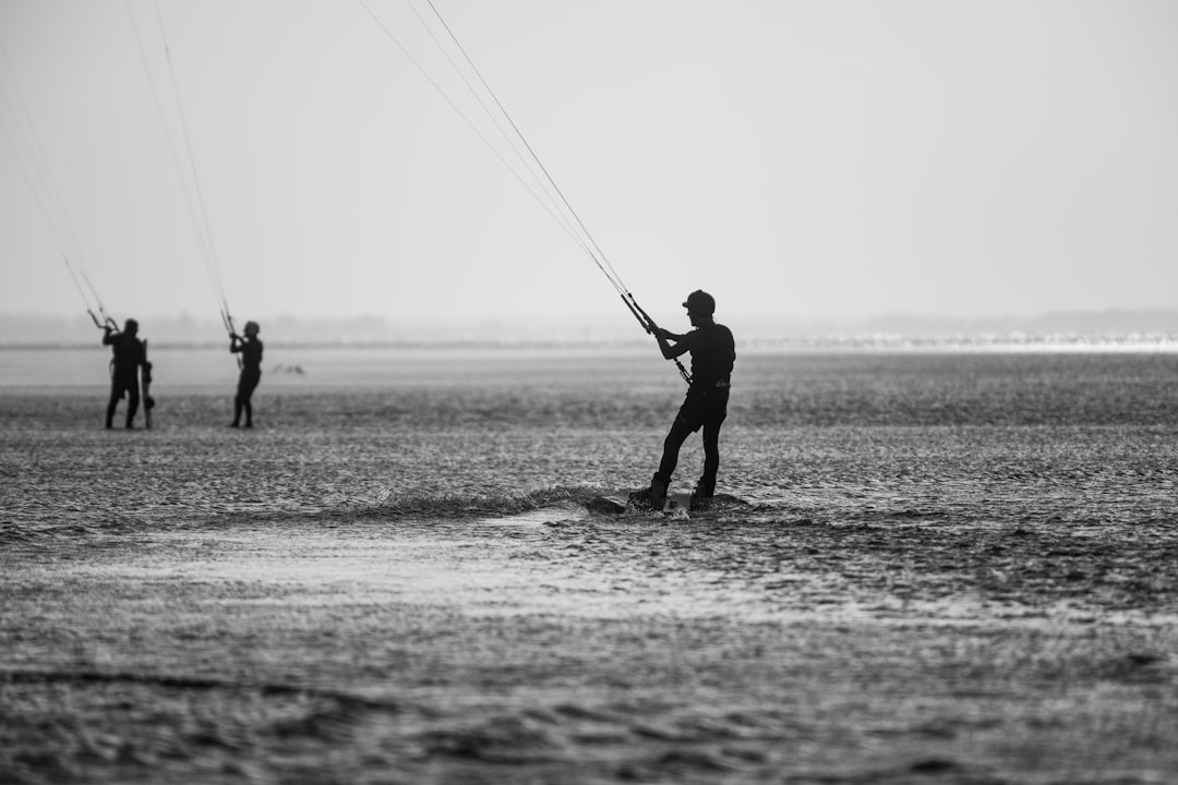 grayscale photo of 2 men fishing on beach