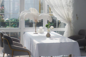 Natural light flooding a room with a table set in crisp white linen tablecloth and napkins.