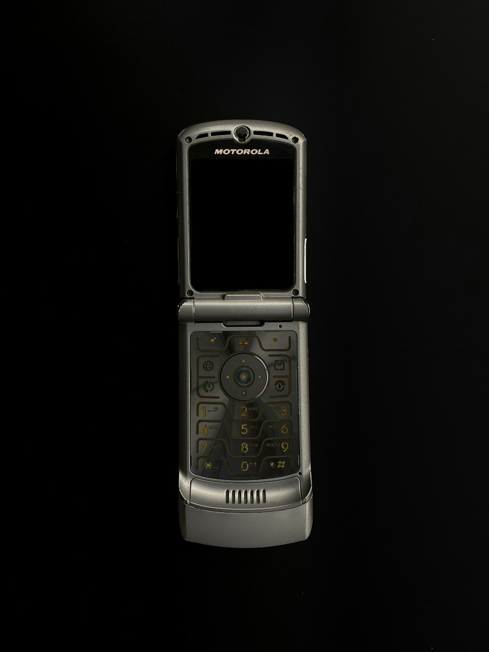 黒い背景に銀の折り畳み式携帯電話