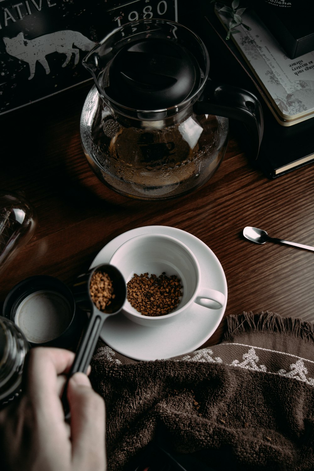 person holding spoon and round white ceramic bowl with brown food