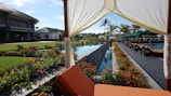 A wide shot of a garden setup featuring a pool, bungalow, and outdoor seating.