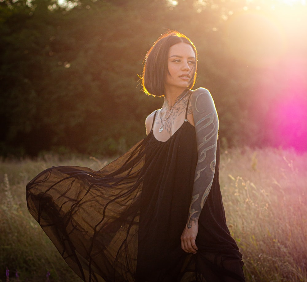 woman in black long sleeve dress standing on green grass field during daytime