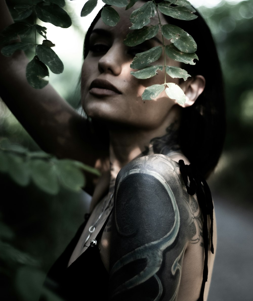 woman in black tank top with green leaves on her face