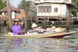 A smiling guide presenting local delicacies to visitors aboard the Juicy Story boat.