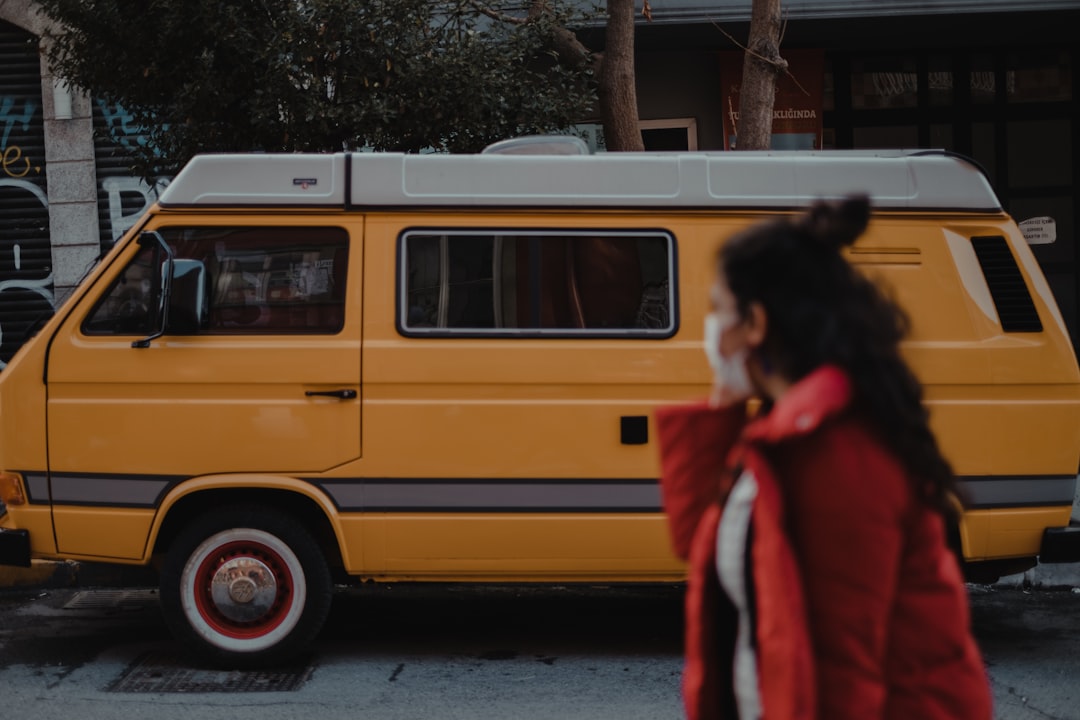 woman in red coat standing beside yellow van