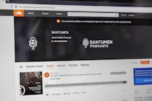 A computer screen displaying a website of an audio streaming service. The website showcases a podcast called BANTUMEN with the description 'Pro Unlimited.' There is a navigation bar with options including Home, Stream, Library, and more. A music wave graphic is visible below, along with a play button, social media interaction options such as re-post, share, and add to playlists. A banner at the top talks about fan-powered royalties, and there is a COVID-19 information widget to the side.