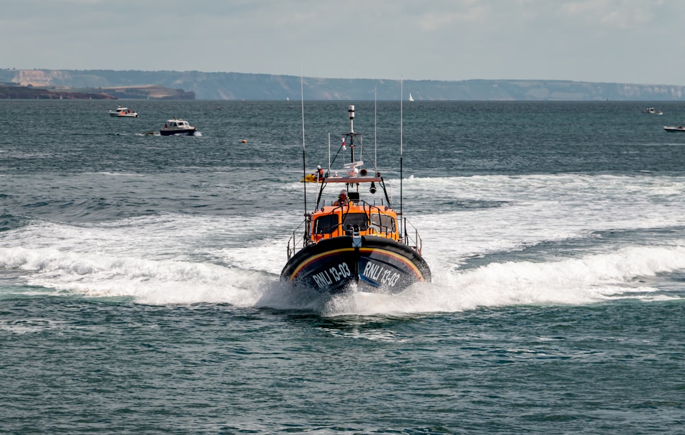 orange and black boat on sea during daytime