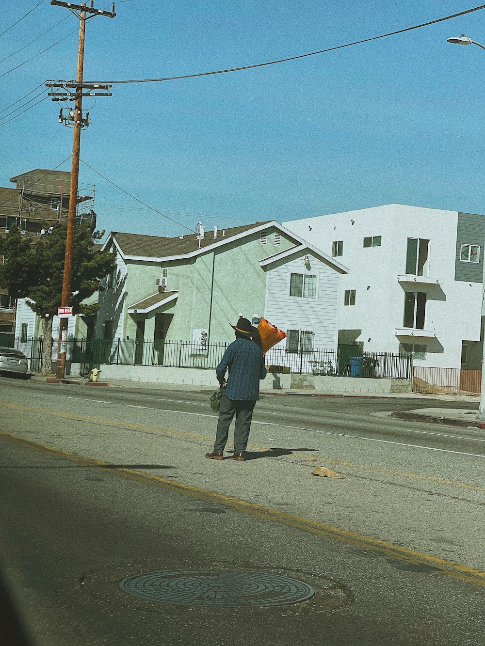 man in black jacket and black pants walking on sidewalk during daytime