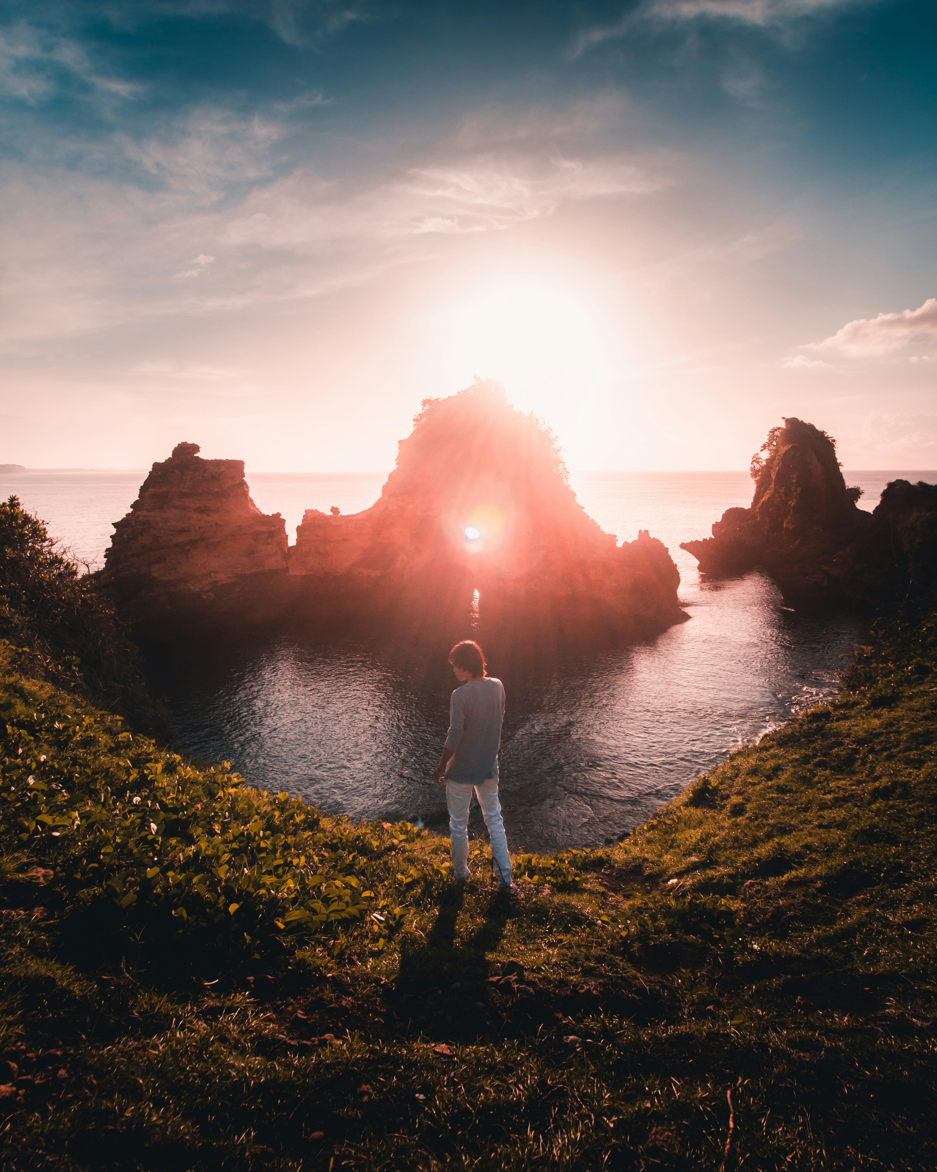 woman in white shirt standing on cliff during sunset