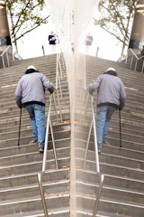 A smiling elderly woman using an Elevita escalator on a sunny staircase outdoors.