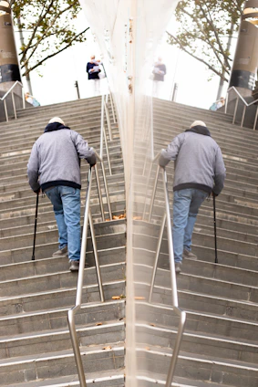 A smiling elderly woman using an Elevita escalator on a sunny staircase outdoors.