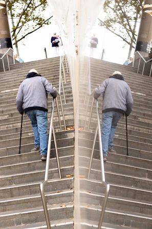 A caring member helping an elderly person carry groceries up the stairs.