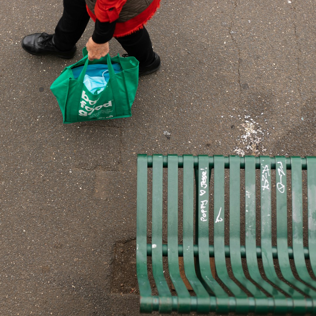 person in black and red jacket sitting on green bench