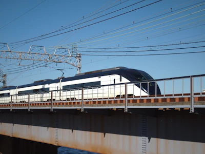 A modern electric train gliding smoothly on polished tracks under a clear sky.