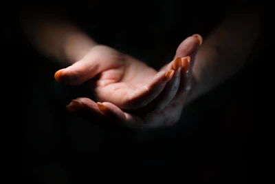 Close-up of hands emitting soft light over a calm natural background.