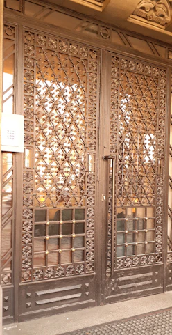 A sturdy, beautifully crafted iron gate with intricate modern patterns at a residential entrance.